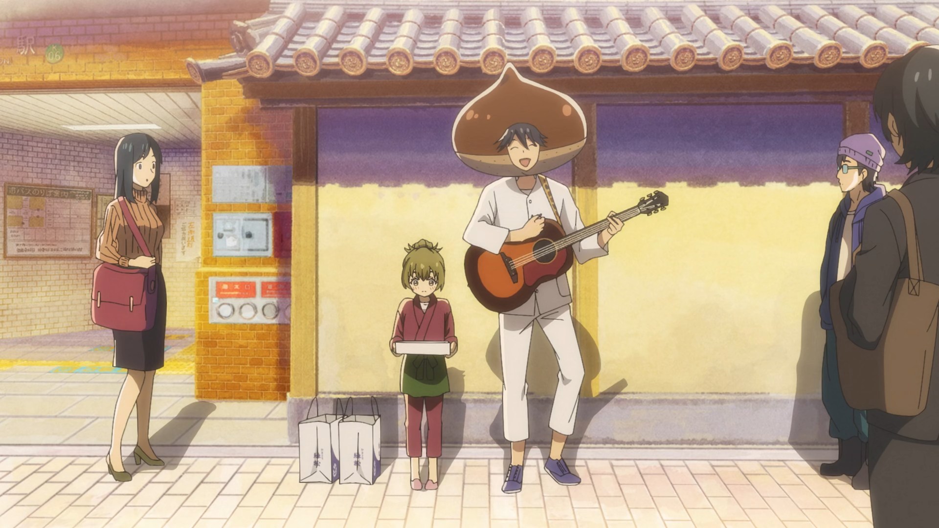 Nagomu in his baker's outfit and with giant chestnut on his head, playing guitar and singing about sweets next to a embarrassed looking Itsuka.